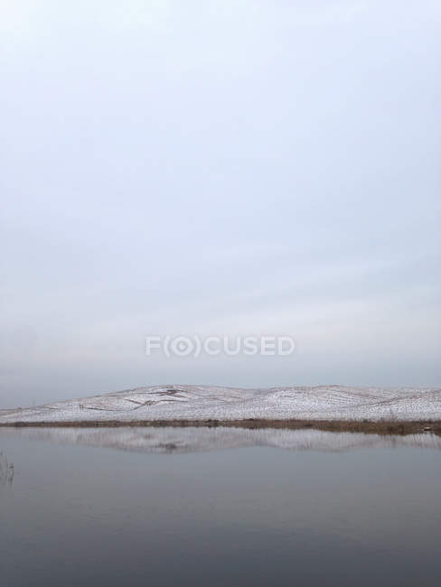 Vista de invierno del lago con colinas en el fondo - foto de stock