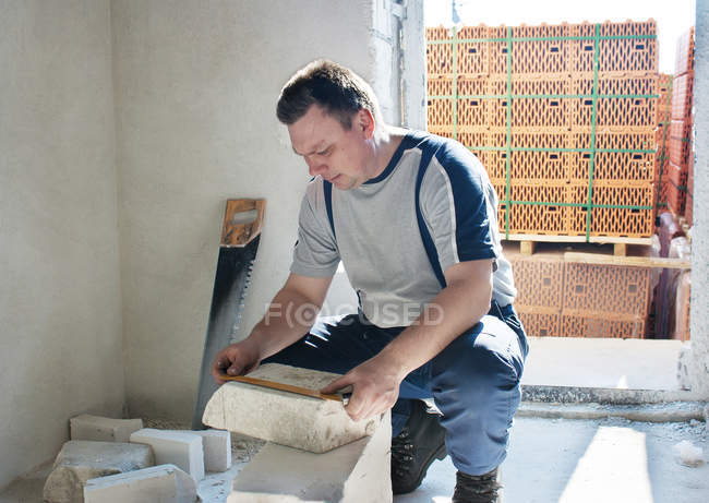 Man measuring a silicate brick with a ruler — Stock Photo
