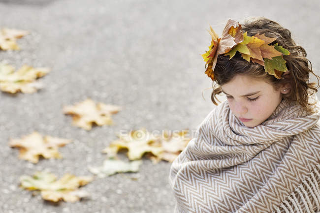 Girl wearing headdress made of autumn leaves and wrapped in scarf — Stock Photo