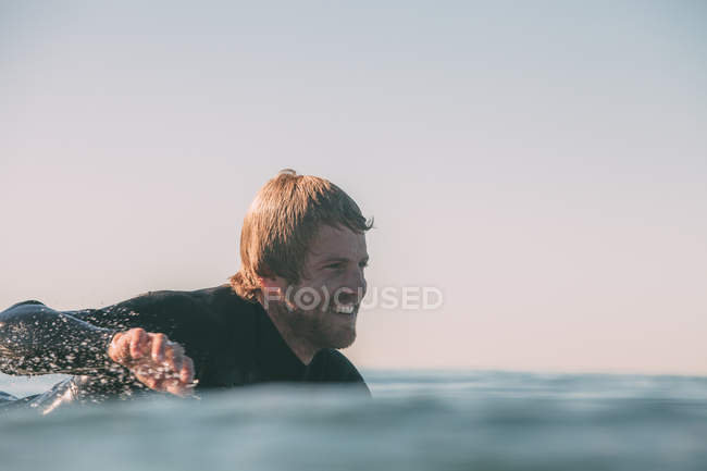 Primo piano di un surfista sorridente che remava per catturare un'onda, San Diego, California, America, USA — Foto stock