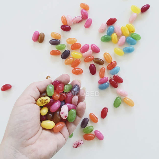 Cropped image of Handful of jelly beans over white table — Stock Photo