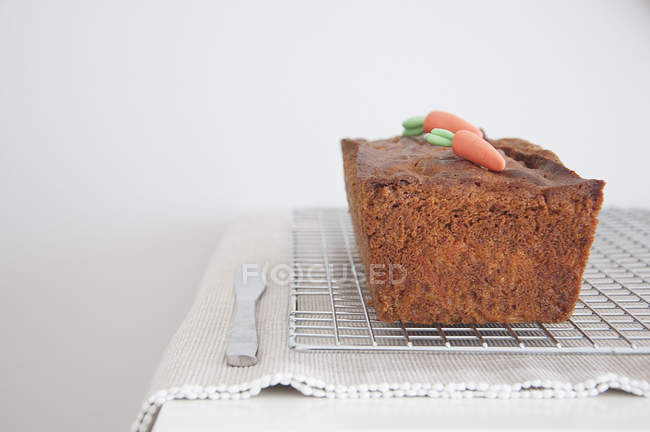 Fresh baked carrot cake cooling on metal rack — Stock Photo
