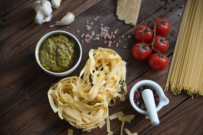 Pasta, pesto, aglio, pomodori e parmigiano in tavola — Foto stock