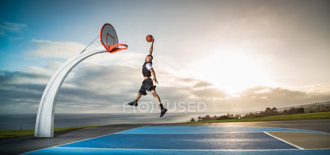 Joven jugando baloncesto en un parque - foto de stock