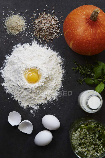 Flour, eggs, milk, herbs, rice, pumpkin and mixed seeds — Stock Photo