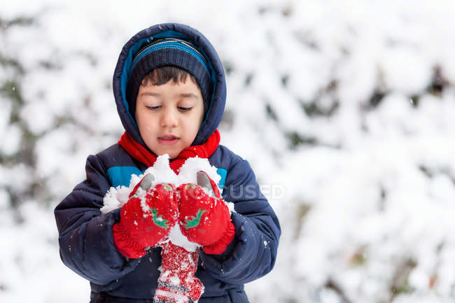 Little boy wearing hooded jacket holding snow — Stock Photo
