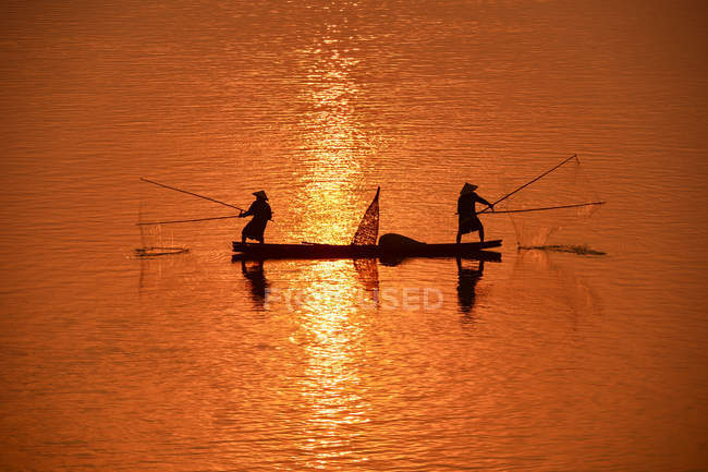 Silhouette di due pescatori in barca sul fiume Mekong, Thailandia — Foto stock