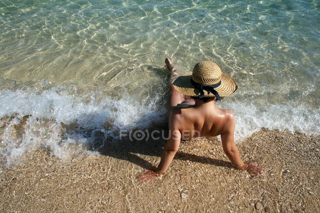 Mulher usando chapéu de palha sentado no surf — Fotografia de Stock