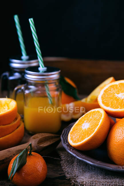 Jugo de naranja recién exprimido y naranjas - foto de stock