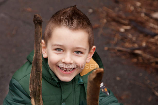 Retrato de niño sonriente sosteniendo palos - foto de stock