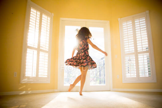 Jeune femme dansant dans une chambre ensoleillée — Photo de stock