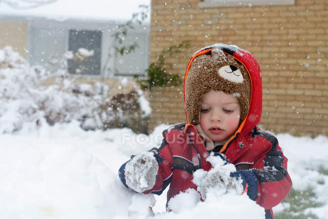 Menino edifício boneco de neve no jardim — Fotografia de Stock