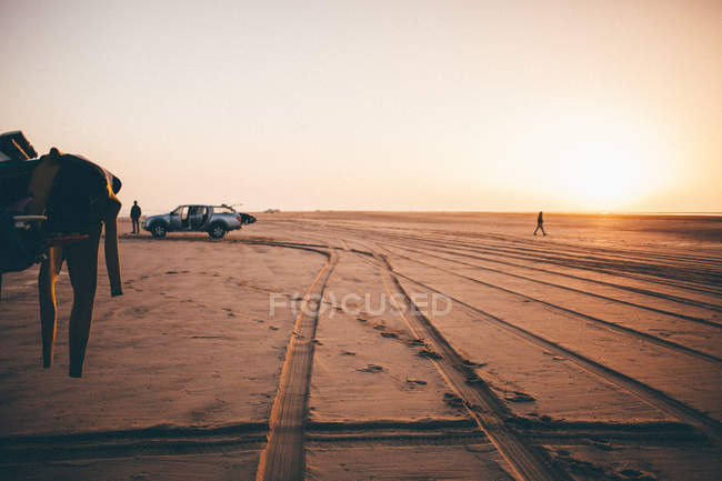 Silhouette of two surfers and car on the beach at sunrise, namibia — Stock Photo