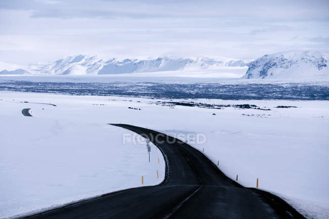 Serpentinenstraße durch verschneite Winterlandschaft, Island — Stockfoto