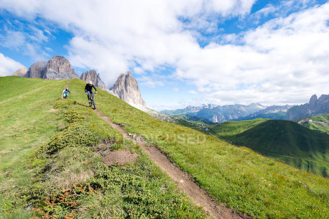 Man and woman mountain biking along trail, Dolomites, Italy — Stock Photo