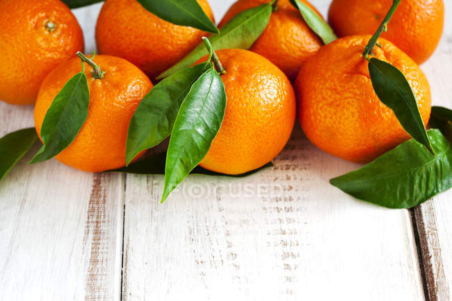 Fresh tangerines with leaves on wooden table — Stock Photo