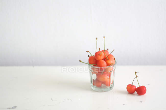 Glass of fresh cherries on white background — Stock Photo