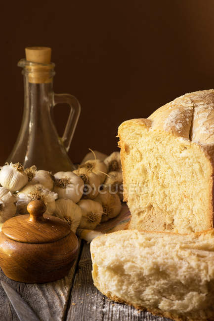 Loaf of bread with olive oil, garlic and salt on rustic wooden table — Stock Photo