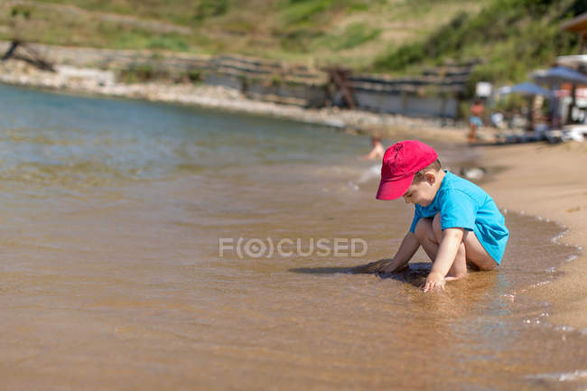Ragazzo con il berretto rosso che gioca sulla spiaggia, Sozopol, Bulgaria — Foto stock