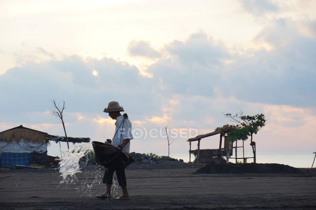 Agricultor de sal salpicando água na areia, bali, indonésia — Fotografia de Stock