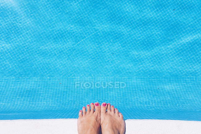 Abgeschnittenes Bild weiblicher Füße am Rande eines Schwimmbades — Stockfoto