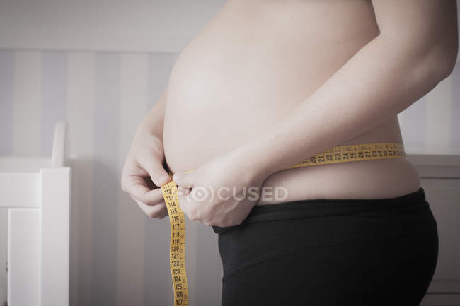 Imagen recortada de Mujer embarazada que mide el vientre - foto de stock