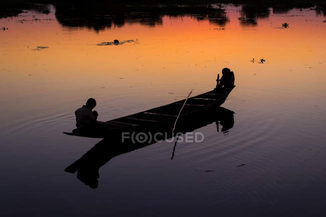 Silueta de personas en barco de pesca en el río - foto de stock