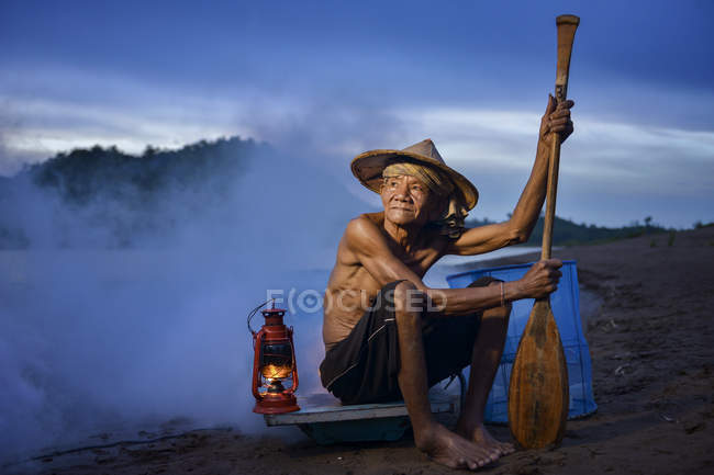 Pêcheur assis dans le bateau au coucher du soleil, Thaïlande — Photo de stock