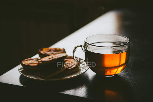 Глянцевий чай і млинці на темному фоні — стокове фото