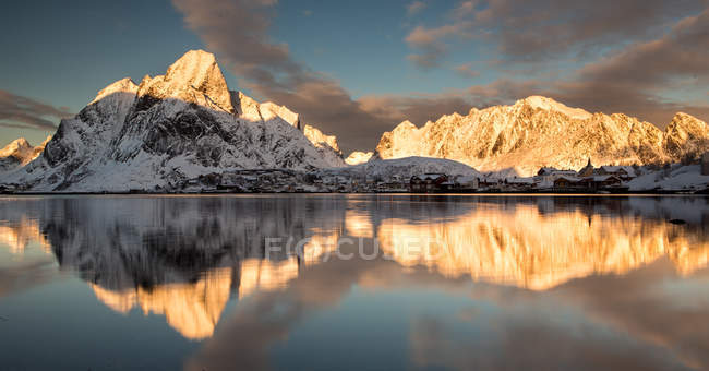 Norway, Lofoten, Reine, Norwegian village and mountains reflecting in water — Stock Photo