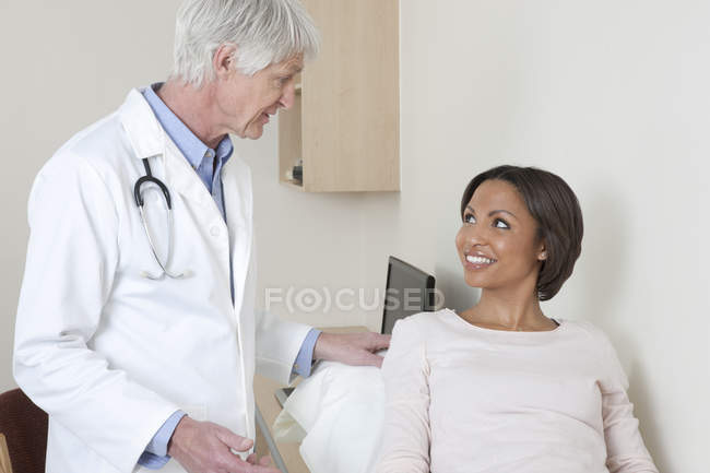 Médecin parlant à une patiente en salle d'examen — Photo de stock