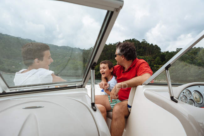 Человек и два мальчика на быстроходной лодке — стоковое фото