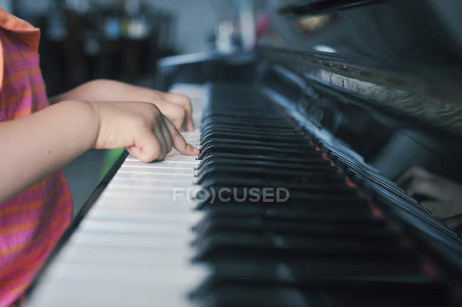 Primeros planos de las manos de una niña tocando el piano - foto de stock