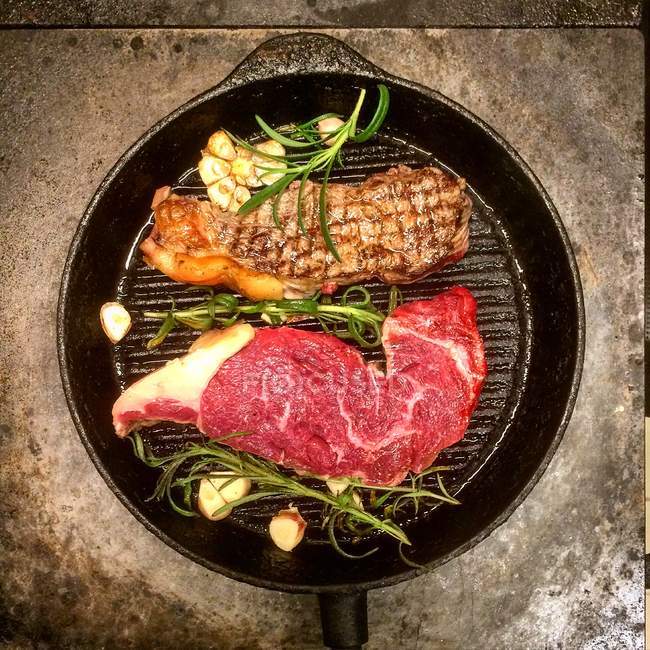Grilled steaks with rosemary and garlic in a frying pan — Stock Photo