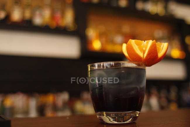 Black cocktail with star shaped orange on bar counter — Stock Photo