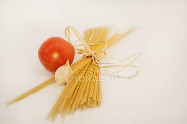 Спагетті, композиція з помідорів і часнику, бежевий фон — стокове фото