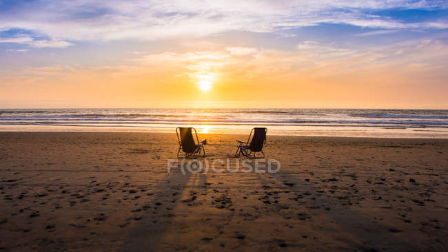 Vista panorámica de dos sillas en la playa al atardecer, California, América, EE.UU. - foto de stock