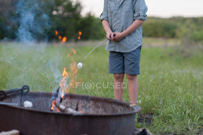 Close-up of Boy toasting a marshmallow over a campfire — Stock Photo