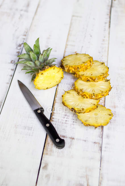 Ananas affettato con coltello su tavolo di legno bianco — Foto stock
