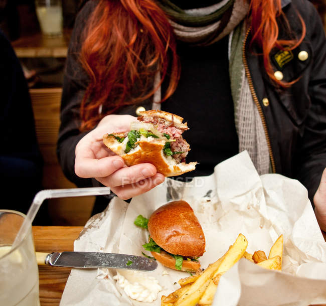 Vue rapprochée d'une femme rousse mangeant un hamburger, section médiane — Photo de stock