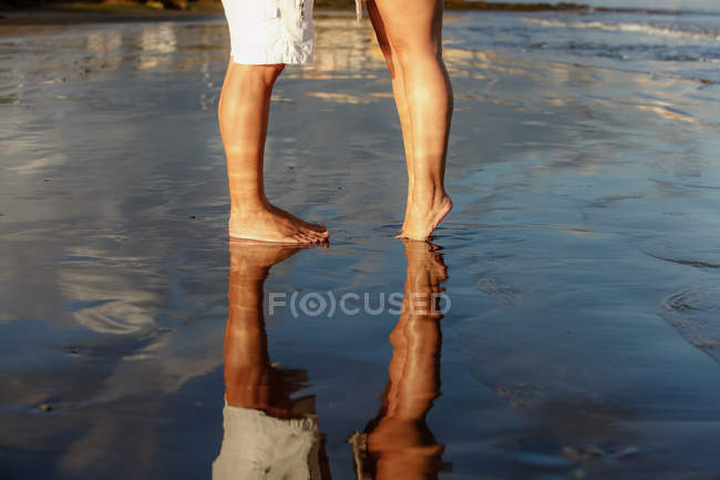 Low-section of young couple standing on beach — Stock Photo