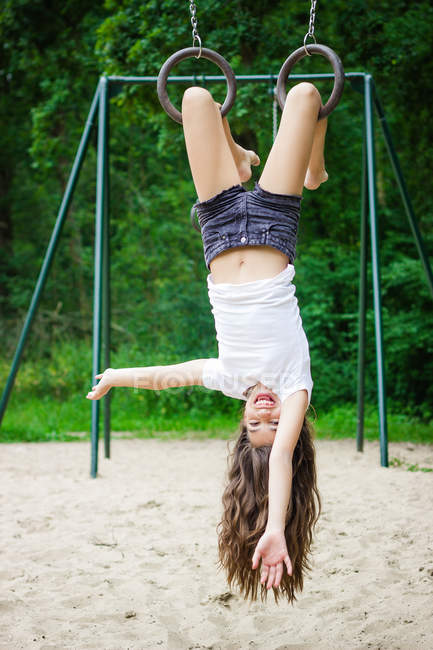Ragazza appesa a testa in giù in un parco giochi — Foto stock