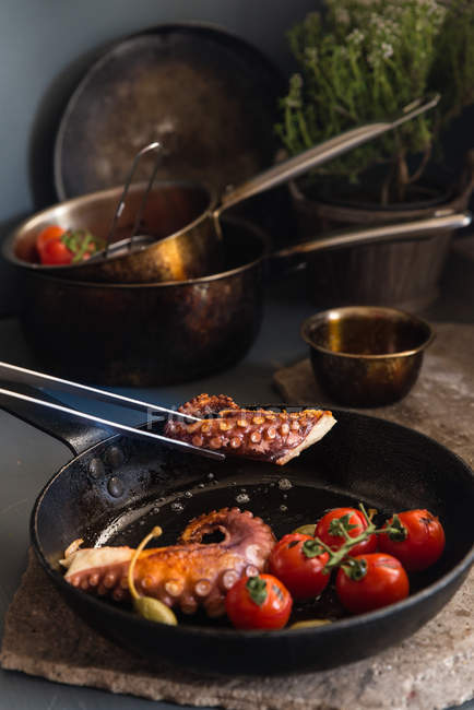 Primer plano Pulpo frito con tomates y alcaparras en sartén negra - foto de stock
