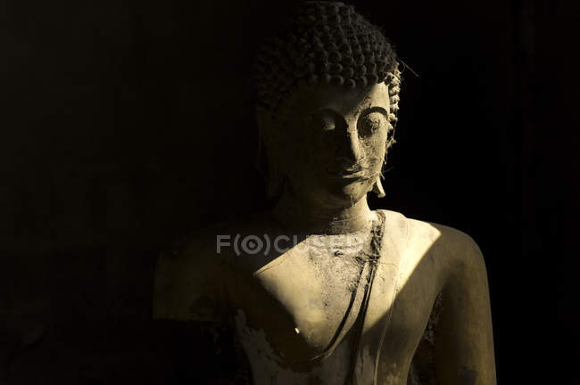 Buda frente a un rayo de luz, estatua de piedra de Buda - foto de stock