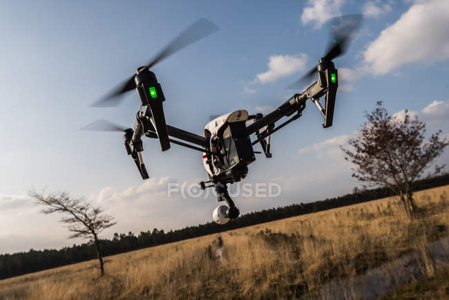 Беспилотник летит в воздухе против красивого полевого пейзажа — стоковое фото