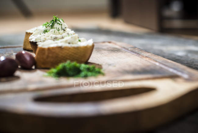 Брускетта с мягким сливочным сыром и оливками на доске — стоковое фото
