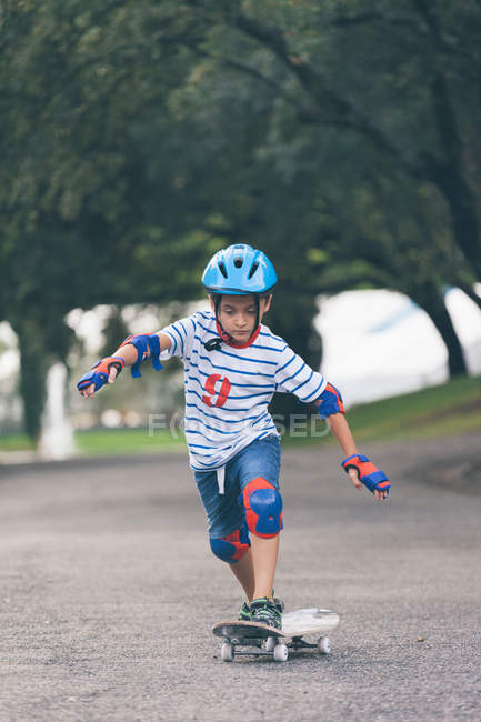 Парень в шлеме катается на скейтборде в парке — стоковое фото