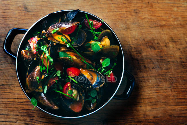 Saucepan with mussels, tomatoes and herbs, top view — Stock Photo