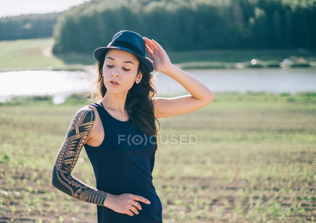 Hipster-Frau mit Tätowierärmel steht in ländlicher Landschaft — Stockfoto