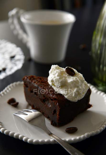Chocolate cake with whipped cream over wooden table — Stock Photo